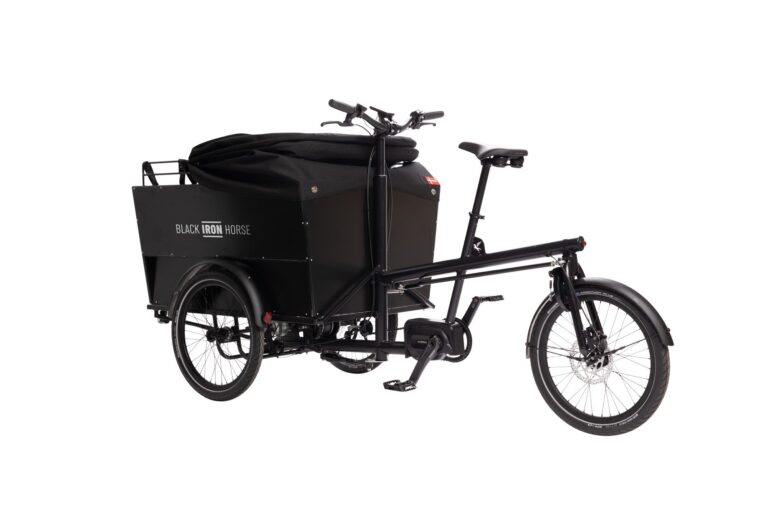 Left side of rear wheel steered cargo bike for six children with the rain cover down